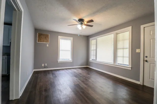 a view of an empty room with wooden floor and a window