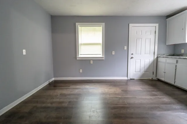 a view of an empty room with window and wooden floor