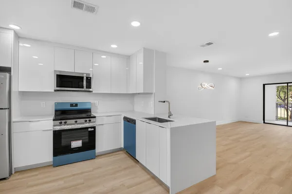 a kitchen with stainless steel appliances granite countertop a stove top oven a sink and a microwave