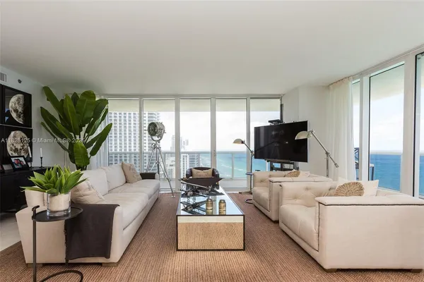 a kitchen with a table a chandelier and living room view