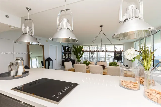 a kitchen with a table a chandelier and living room view