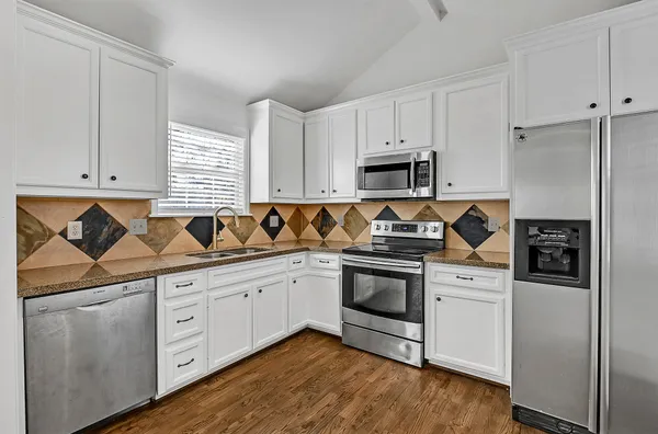 a kitchen with granite countertop white cabinets and stainless steel appliances