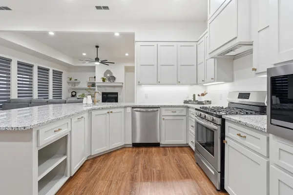 a kitchen with stainless steel appliances granite countertop a stove a sink dishwasher and a refrigerator with wooden floor