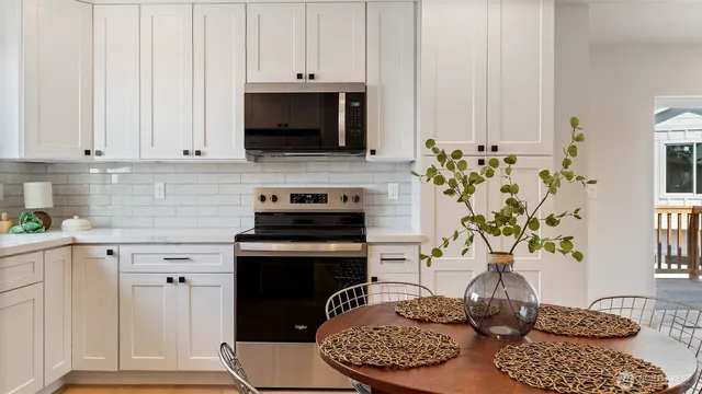 a kitchen with stainless steel appliances granite countertop a stove a white cabinets a dining table and chairs