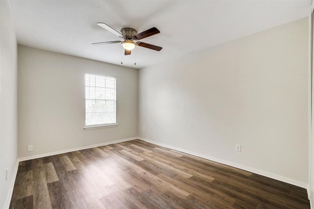1105 UTA Boulevard, Unit 102 Arlington, TX 76013 - Photo 4 of 10 an empty room with wooden floor fan and windows