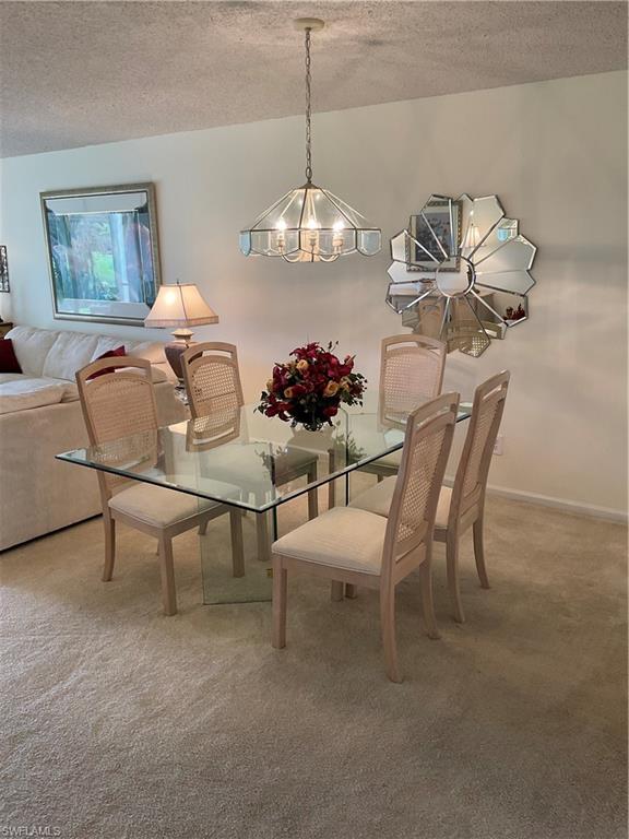 6780 Dennis Circle, Unit M103 Naples, FL 34104 - Photo 14 of 23 a view of a dining room with furniture and chandelier