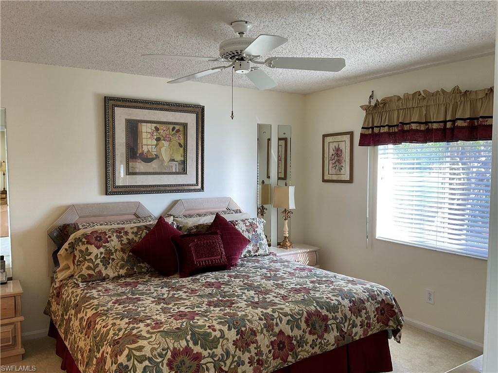 6780 Dennis Circle, Unit M103 Naples, FL 34104 - Photo 6 of 23 a bedroom with a bed and a chandelier