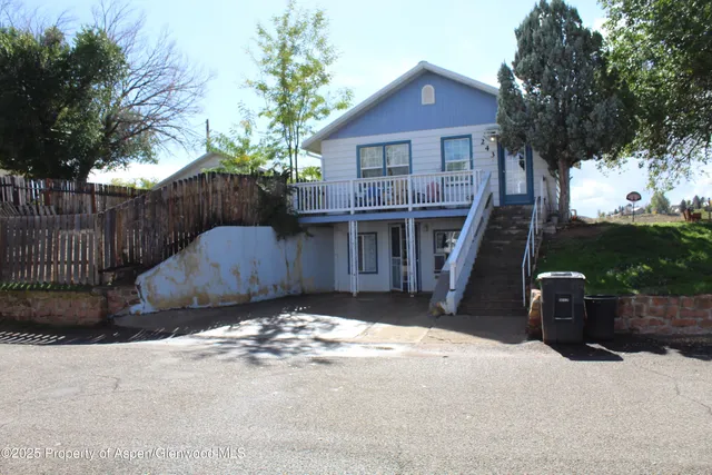 a view of a house with a wooden fence next to a road