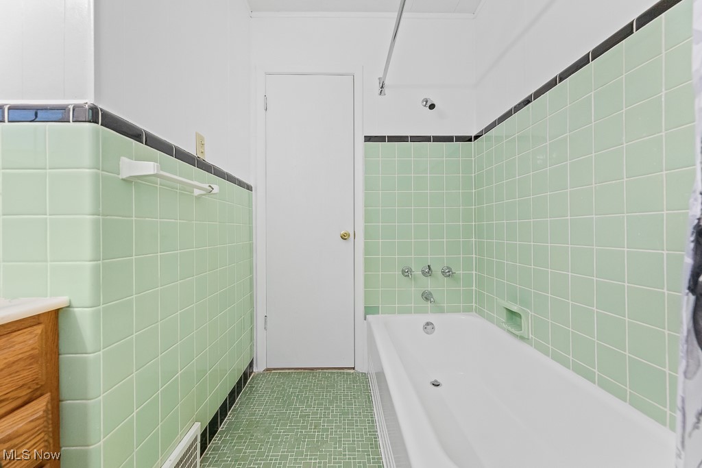 9049 Prospect Road Strongsville, OH 44149 - Photo 20 of 50 Bathroom featuring vanity, tile patterned flooring, tiled shower / bath combo, and tile walls
