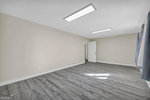 a view of an empty room with wooden floor and a window