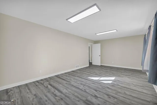 a view of an empty room with wooden floor and a window