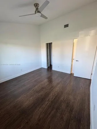 an empty room with wooden floor cabinet and windows