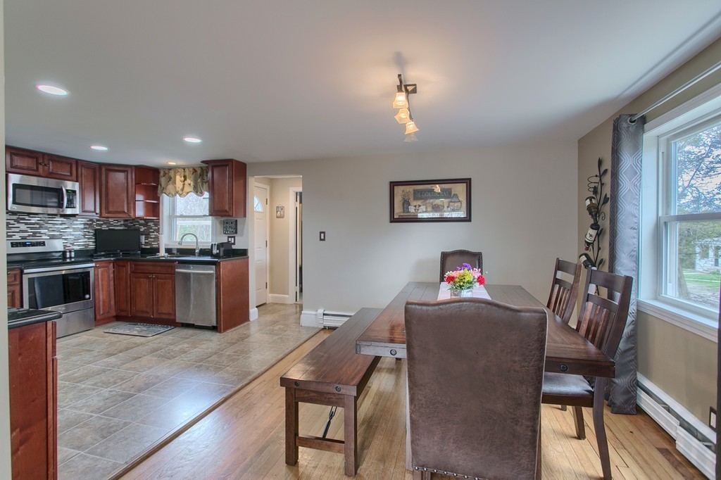547 Boston Road Billerica, MA 01821 - Photo 9 of 23 a kitchen with stainless steel appliances granite countertop a stove top oven a sink a dining table and chairs