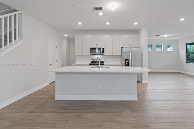 a view of kitchen with kitchen island stainless steel appliances sink and cabinets