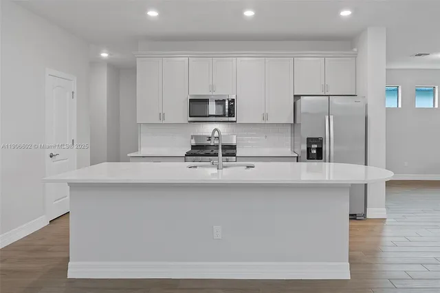 a kitchen with stainless steel appliances a sink a stove a refrigerator and cabinets