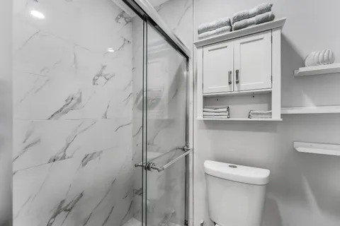 a bathroom with a refrigerator a toilet and a sink