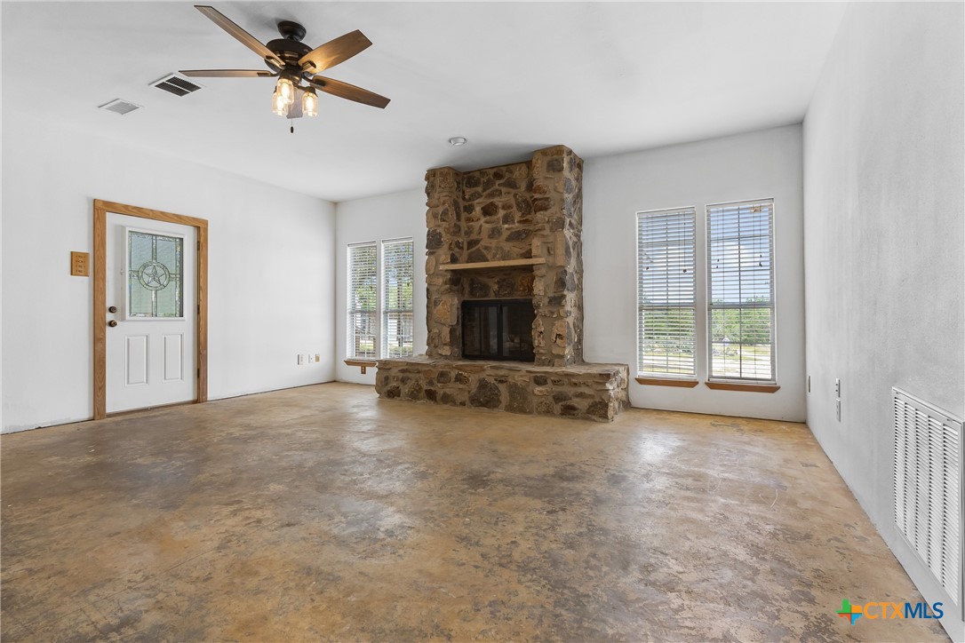 700 Camino De Rancho Wimberley, TX 78676 - Photo 10 of 41 an empty room with windows fireplace and fan