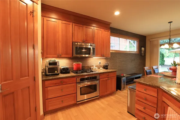 a kitchen with stainless steel appliances granite countertop wooden cabinets and a stove top oven
