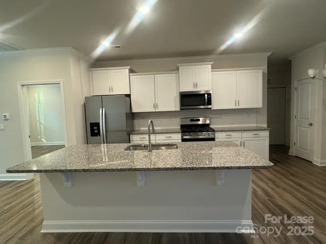 a kitchen with stainless steel appliances granite countertop a sink a stove a refrigerator a microwave and cabinets