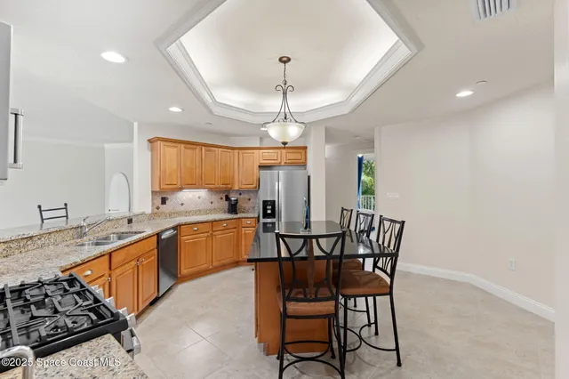a kitchen with stainless steel appliances a dining table chairs and white cabinets