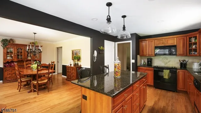 a kitchen with stainless steel appliances granite countertop a stove top oven a dining table and chairs with wooden floor