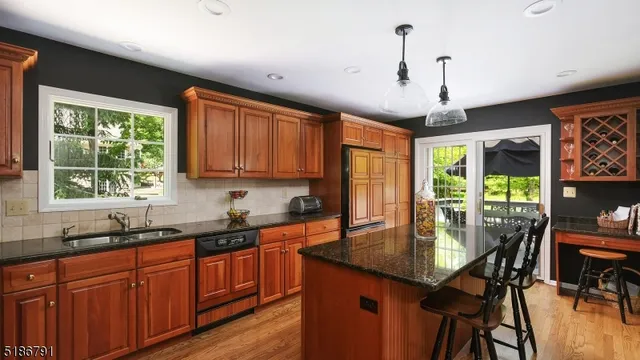 a kitchen with stainless steel appliances granite countertop wooden cabinets a stove a sink a dining table and chairs