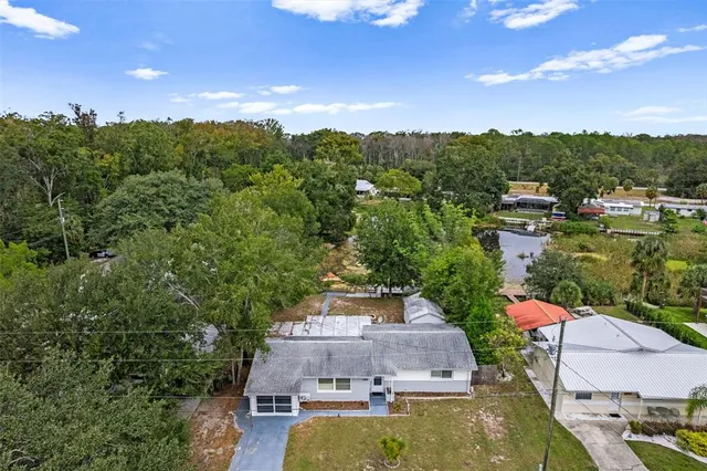 an aerial view of a house with garden space and trees all around
