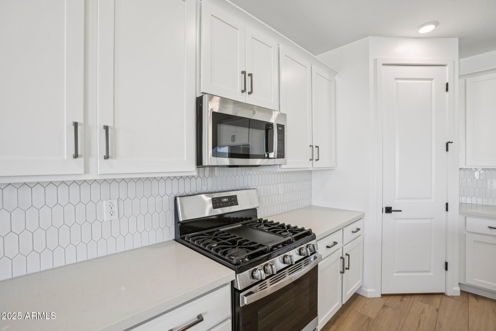 16226 West Bajada Road Surprise, AZ 85387 - Photo 13 of 45 a kitchen with white cabinets and stainless steel appliances