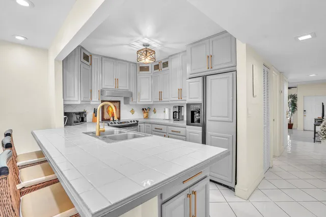 a kitchen with a refrigerator a stove top oven a sink dishwasher and white cabinets