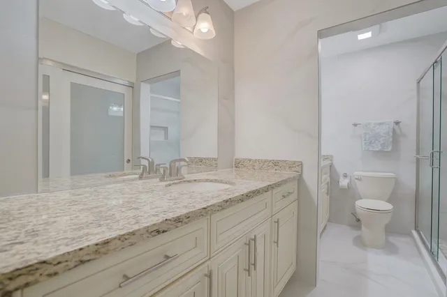 a bathroom with a granite countertop toilet sink and mirror