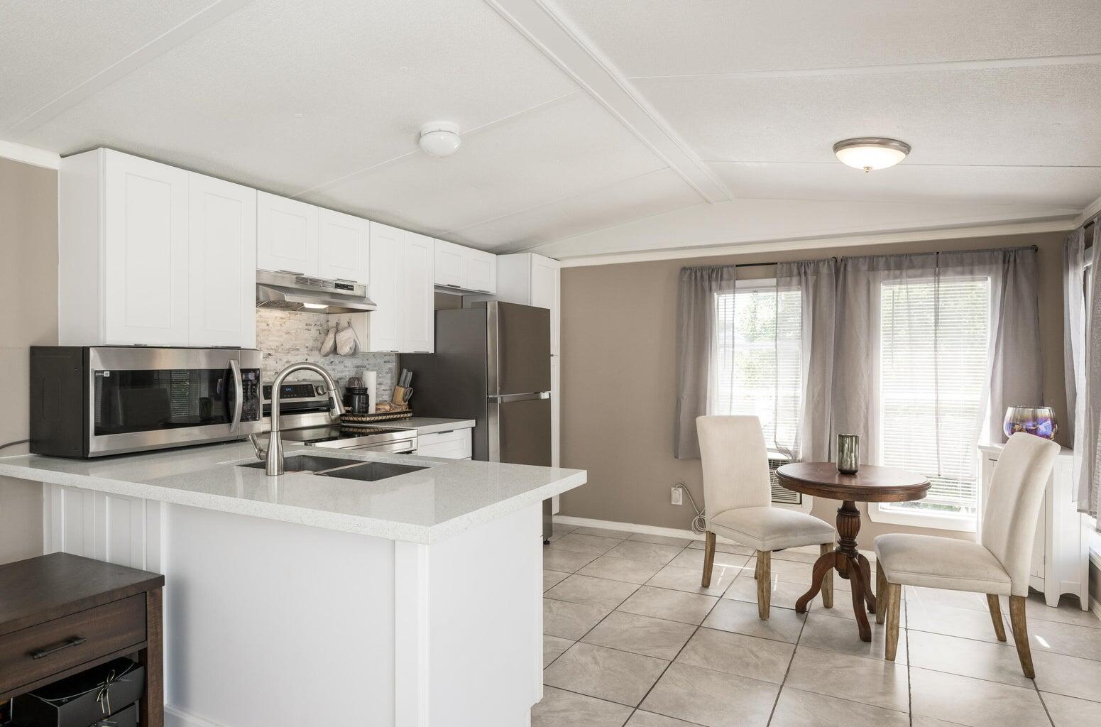 27942 Snapper Lane Summerland Key, FL 33042 - Photo 11 of 26 a kitchen with stainless steel appliances kitchen island granite countertop a stove a refrigerator a microwave a dining table and chairs