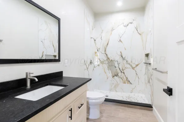 a bathroom with a granite countertop sink a toilet and a shower