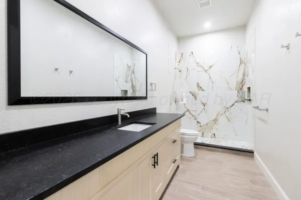 a bathroom with a granite countertop sink a toilet and a bathtub