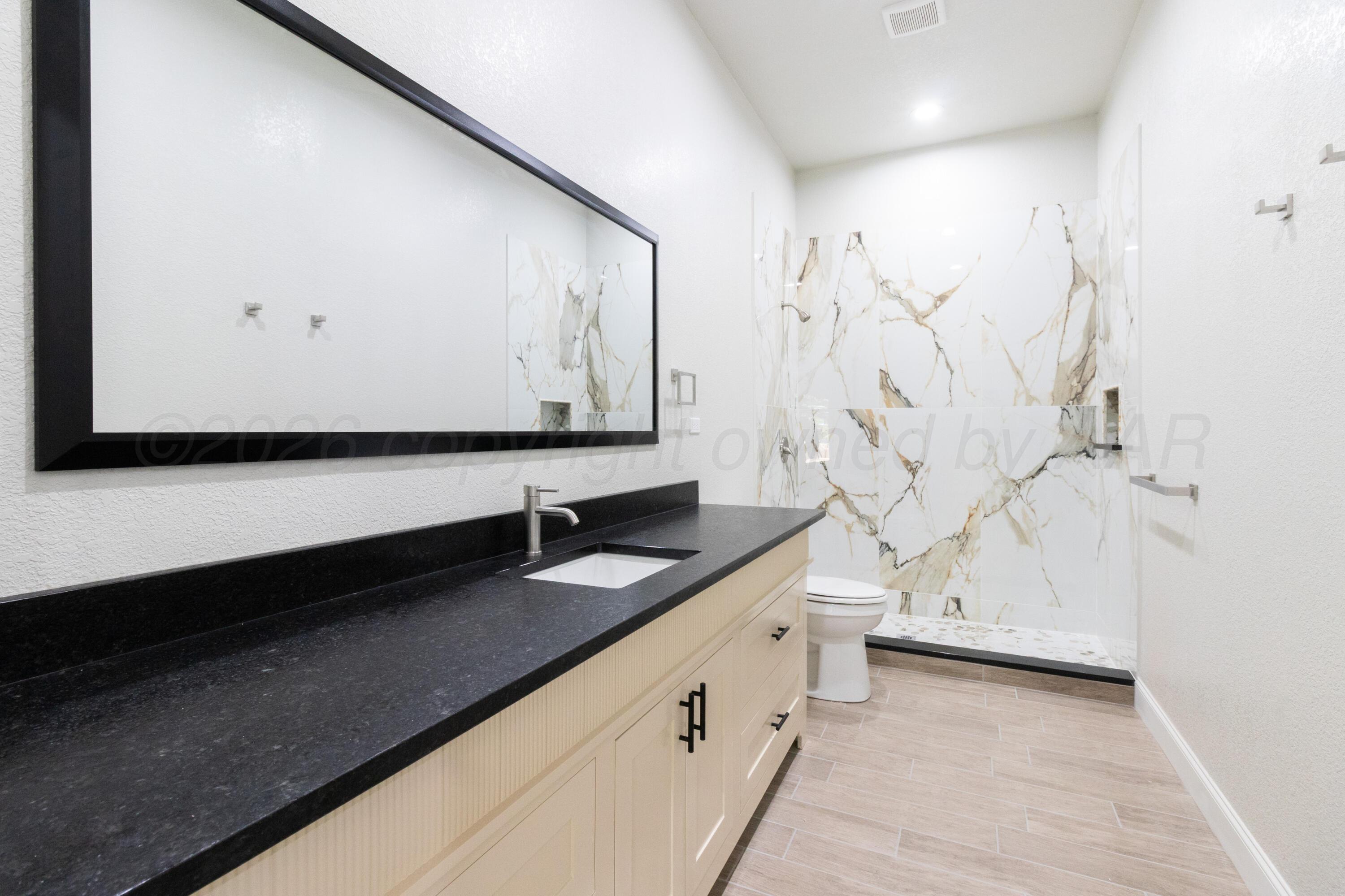 810 South Houston Street Shamrock, TX 79079 - Photo 26 of 42 a bathroom with a granite countertop sink a toilet and a bathtub