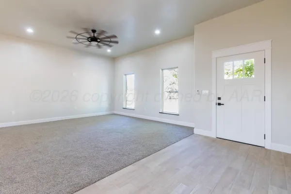 an empty room with chandelier fan and windows