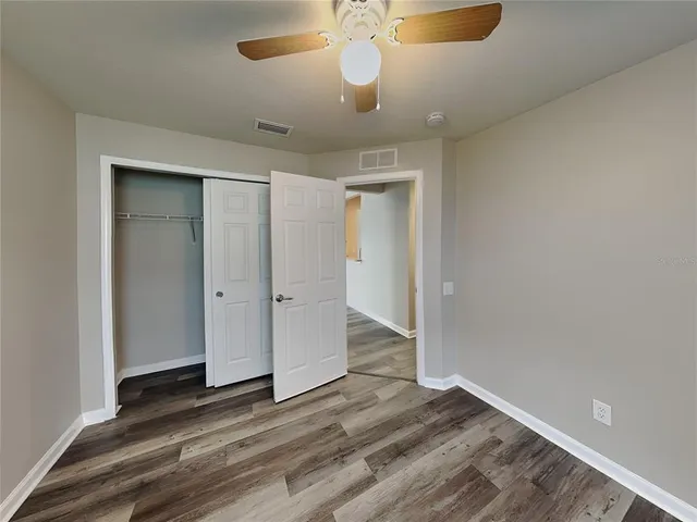 wooden floor in an empty room with a chandelier fan
