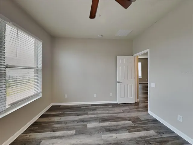 a view of an empty room with wooden floor and window