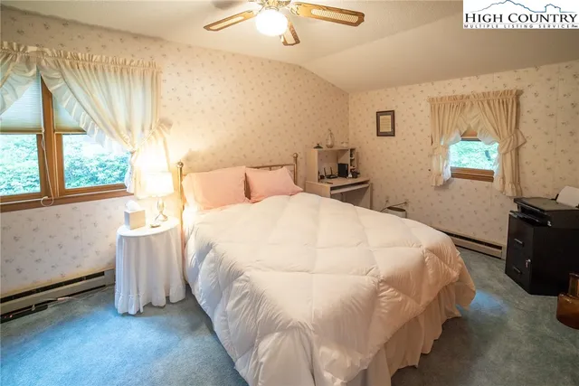 a large white bed in a bedroom next to a window