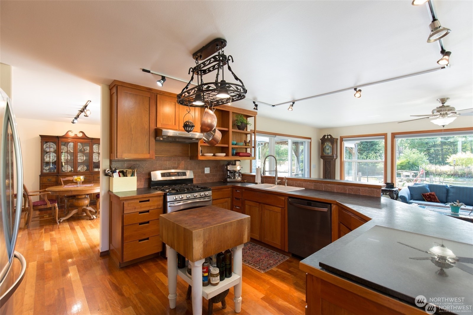 61 Camelot Road Sequim, WA 98382 - Photo 11 of 33 a kitchen with granite countertop a stove a sink a dining table and chairs with wooden floor