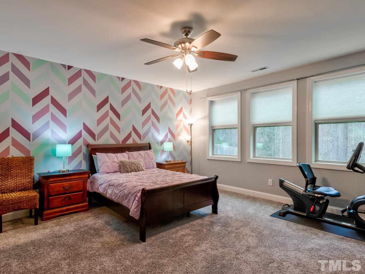 8325 Henderson Road Apex, NC 27539 - Photo 21 of 29 a bedroom with a bed and a chandelier