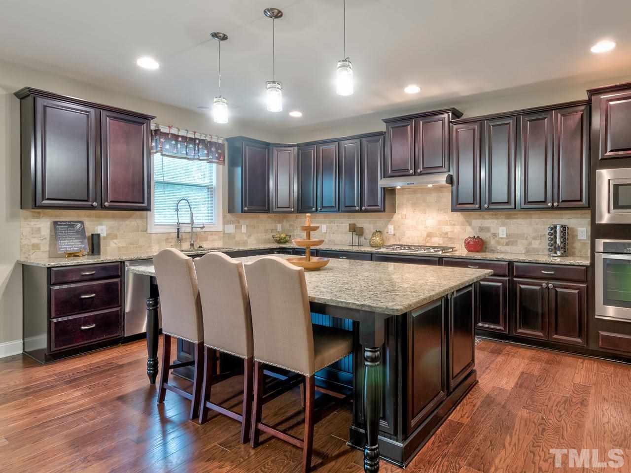 8325 Henderson Road Apex, NC 27539 - Photo 6 of 29 a kitchen with granite countertop wooden floors appliances and cabinets