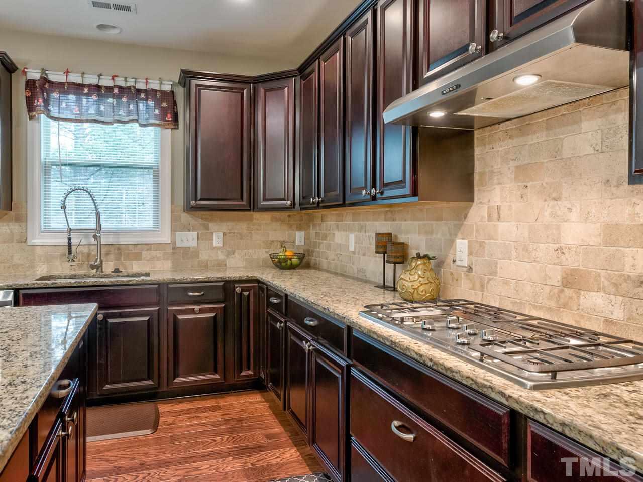 8325 Henderson Road Apex, NC 27539 - Photo 7 of 29 a kitchen with stainless steel appliances granite countertop a stove a sink dishwasher and cabinets with wooden floor