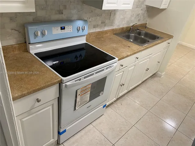 a kitchen with granite countertop white cabinets and white appliances