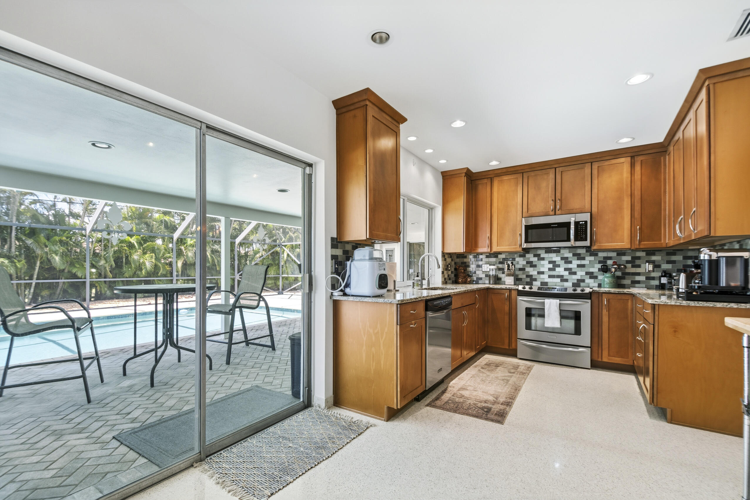 1348 Southwest 4th Street Boca Raton, FL 33486 - Photo 13 of 44 a kitchen with stainless steel appliances granite countertop a stove a refrigerator a sink a dining table and chairs with wooden floor