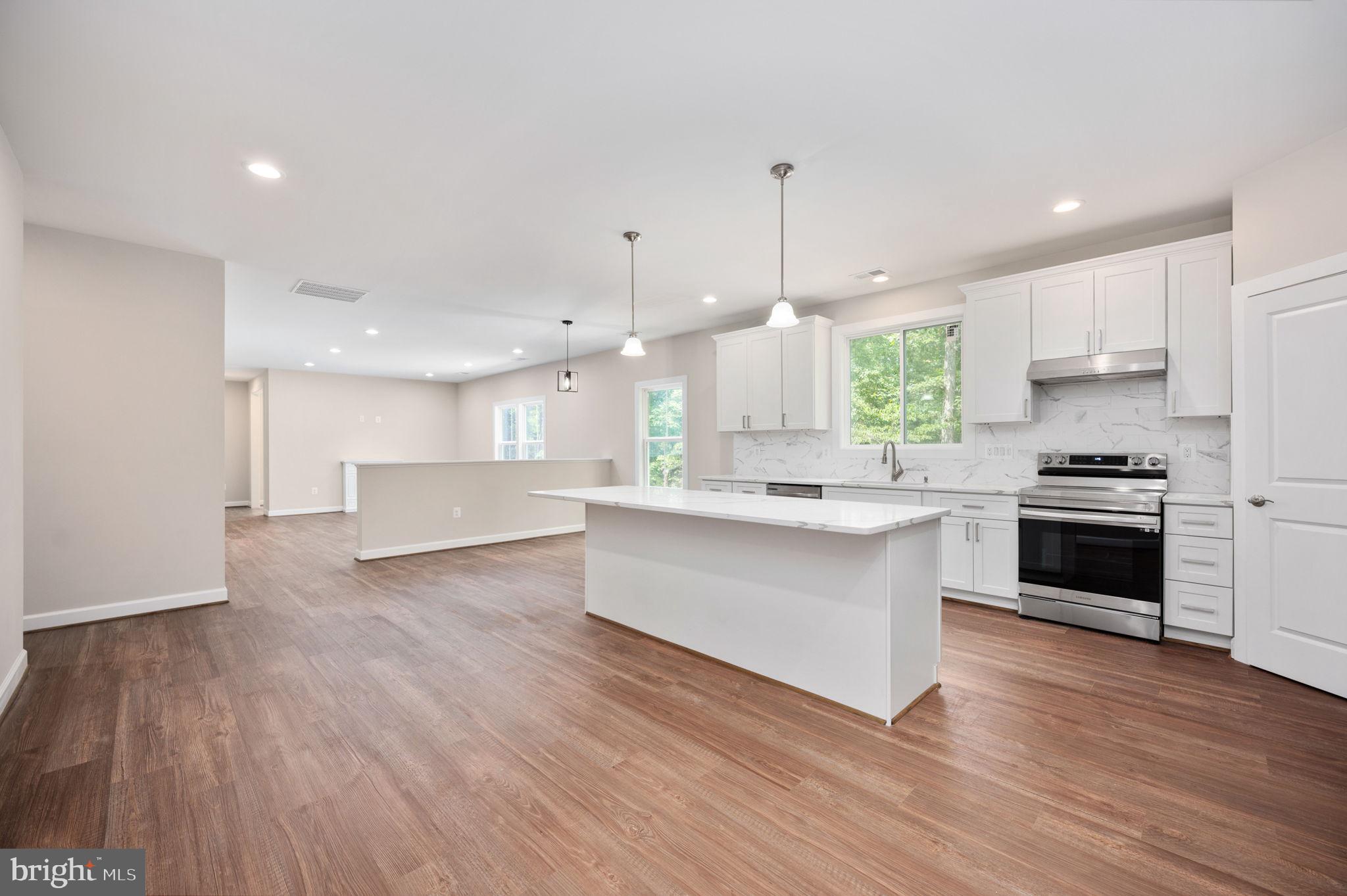 107 Gold Valley Road Locust Grove, VA 22508 - Photo 3 of 19 a kitchen with stainless steel appliances kitchen island wooden floors and white cabinets