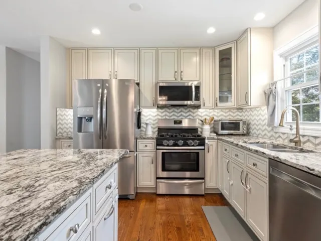 a kitchen with stainless steel appliances granite countertop a stove refrigerator sink and microwave