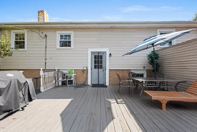 a view of a roof deck with table and chairs a barbeque with wooden floor and fence