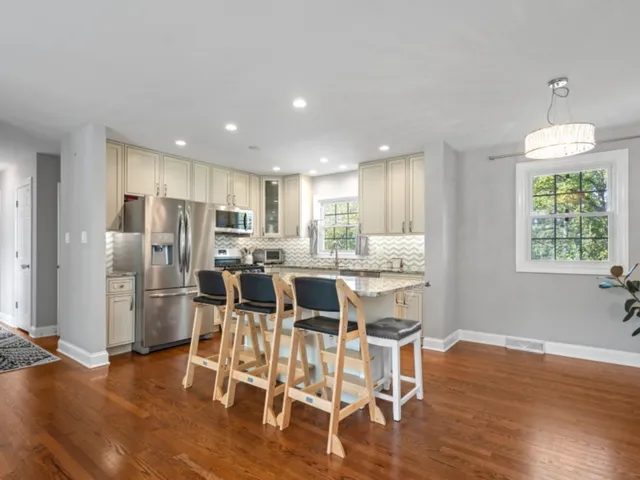 a kitchen with stainless steel appliances kitchen island granite countertop a refrigerator and a dining table chair