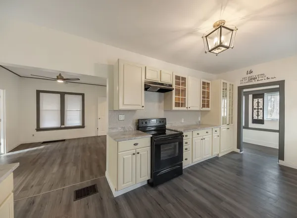 a kitchen with granite countertop a stove top oven a sink dishwasher and wooden cabinets with wooden floor