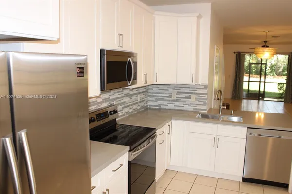 a kitchen with granite countertop white cabinets and white appliances